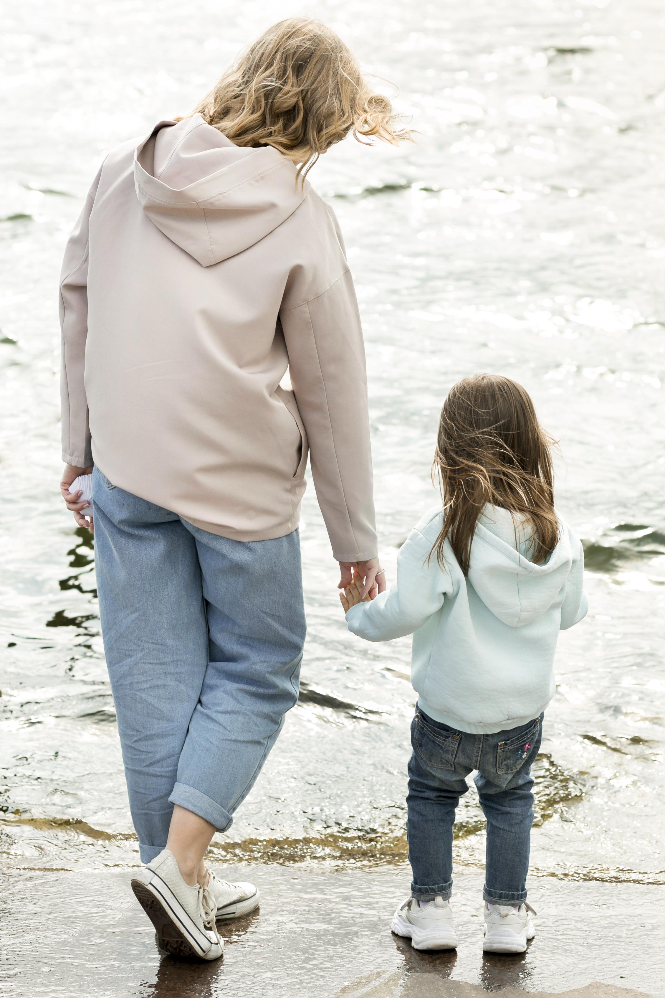 Madre e hija cogidas de la mano paseando por la orilla del mar en Peñíscola