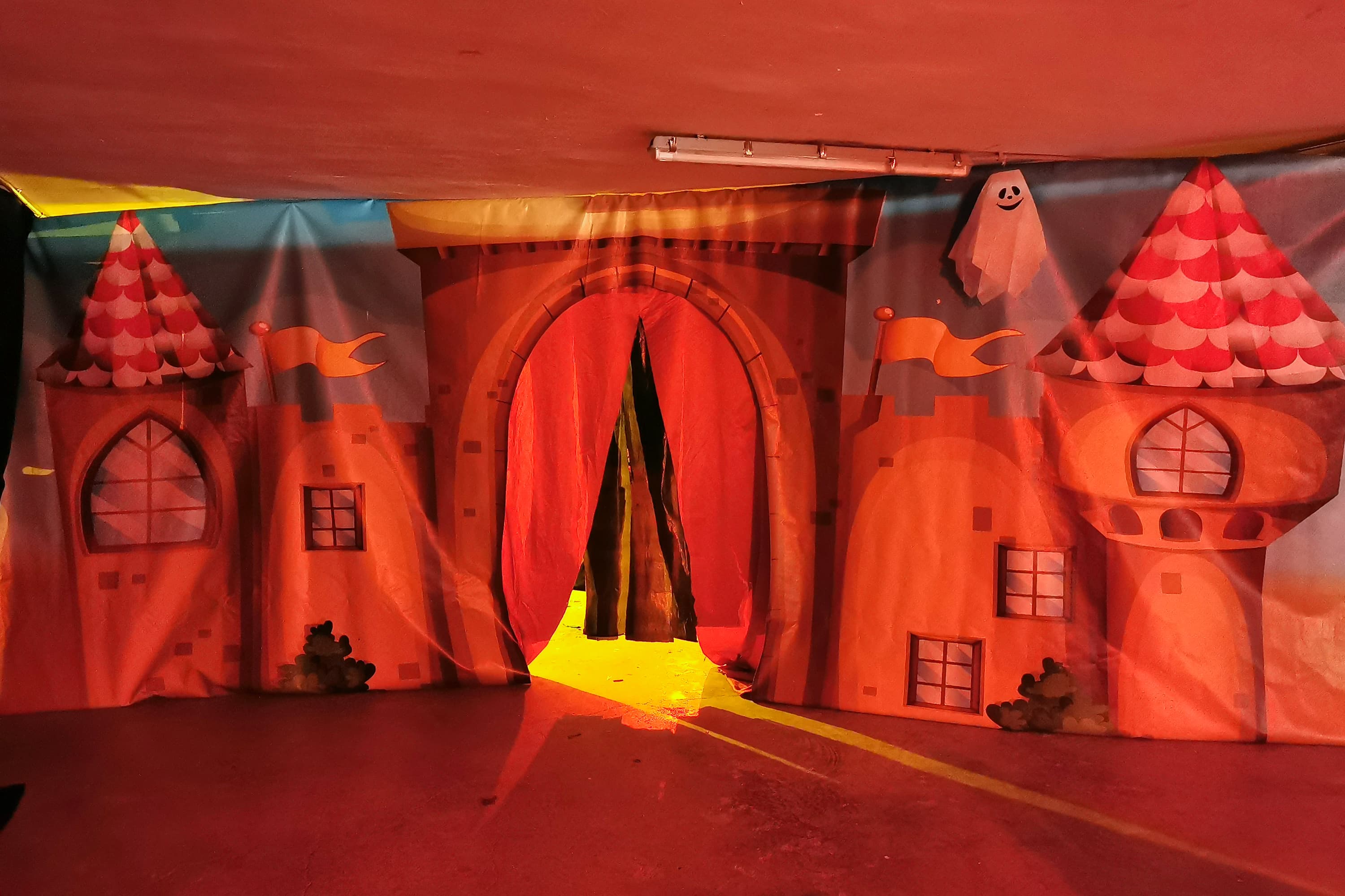 Entrada decorada tipo castillo embrujado con telón rojo y fantasma — escenografía para túnel del terror infantil